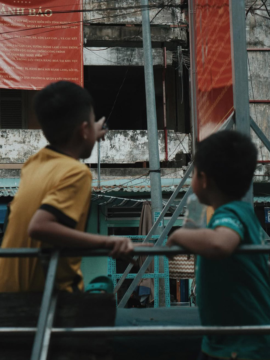 two kids playing on the ground pointing at the apartment