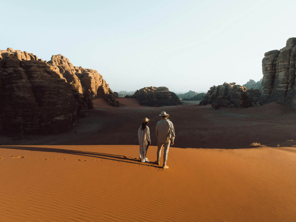 A couple walking on the dessert, turning their back to the camera.